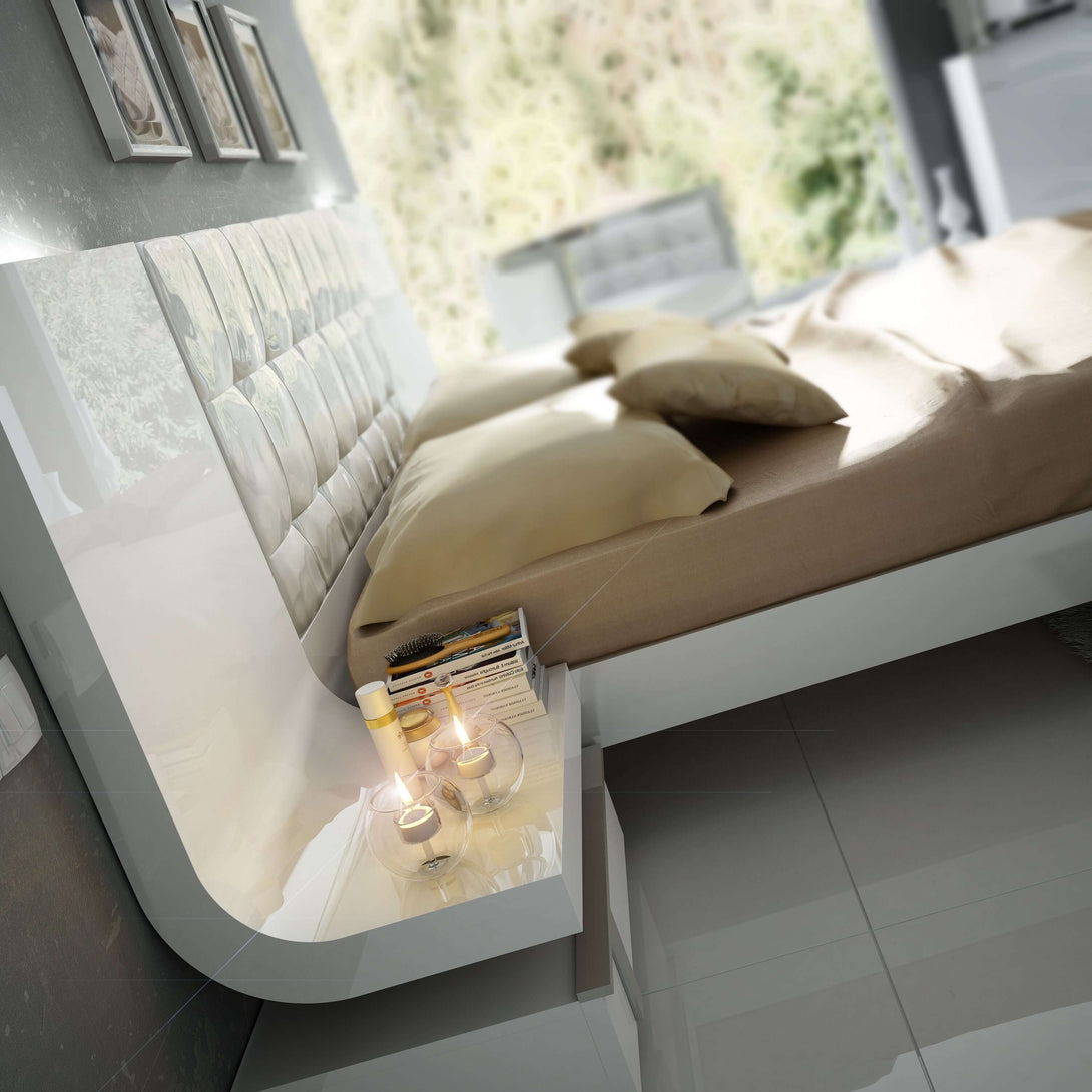 Modern bed with a nightstand drawer open, revealing books and a glass.